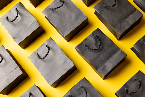 Složení nákupních tašek z šedého papíru na žlutém pozadí. Maloobchod, nakupování a černý pátek koncept. - Fotografie, Obrázek