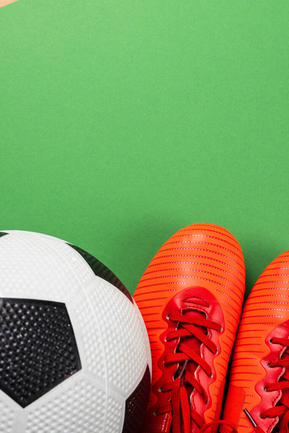 Image of orange football boots and football on green background with copy space. Sports and competition concept. - Φωτογραφία, εικόνα