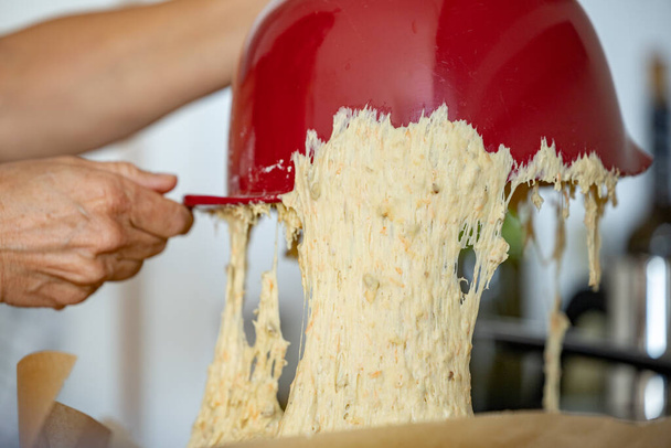 Brooddeeg rijzen en gist in een keukenkom wordt gegoten op een ovenschaal. - Foto, afbeelding