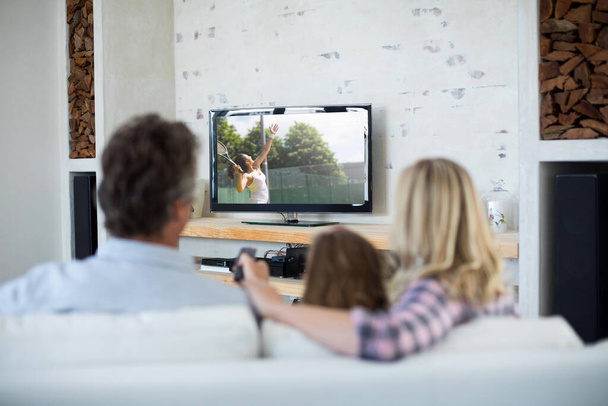 Rear view of family sitting at home together watching tennis match on tv. sports, competition, entertainment and technology concept digital composite image. - Foto, Imagem