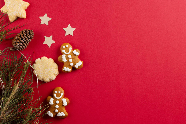 Image of gingerbread man biscuits and christmas decoration with copy space on red. Christmas, tradition and celebration concept. - Foto, Bild