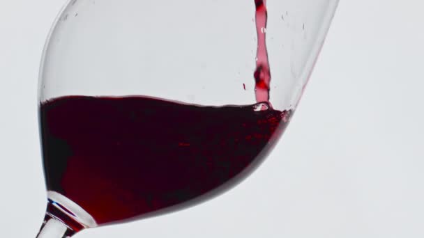 Kaatamalla punaista nestemäistä lasia lähikuva. Tuore alkoholijuoma kuplivaa viinilasia. Luonnollinen virkistävä cabernet viini täyte puhdas pikari. Gourmet hedelmä viinaa roiskeita perustamisesta super hidastettuna  - Materiaali, video