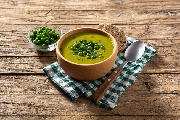 Green pea soup in a bowl on rustic wooden table - Фото, изображение