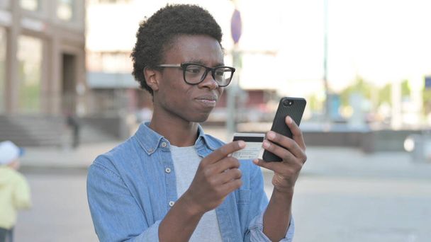 Znepokojit africký muž reagující na ztrátu na Smartphone Outdoor - Fotografie, Obrázek
