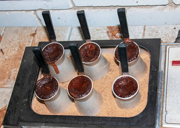 Traditionele Turkse koffie met schuim in cezve bereid op heet zand in authentiek Turks Koper of koffiezetapparaat. - Foto, afbeelding