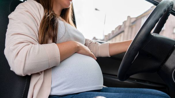 Pregnant driving car. Young smiling pregnancy woman driving car. Safety pregnant young mom driving concept - Foto, Imagem