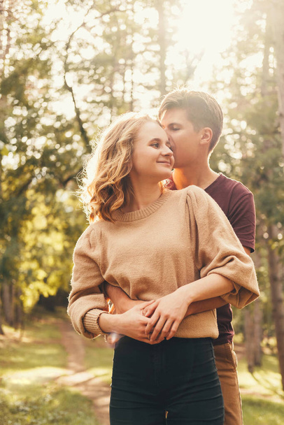 Foto vertical de una linda pareja joven pasando tiempo juntos en el parque. El hombre está abrazando a su mujer. - Foto, imagen