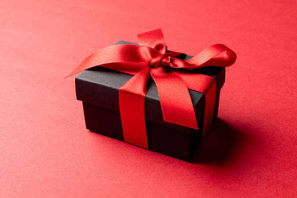 Composition of present with red ribbon on red background. Retail, shopping and black friday concept. - Foto, Bild