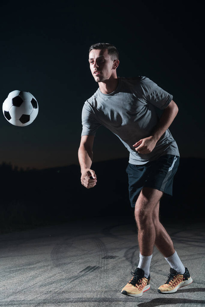 retrato de un joven apuesto jugador de fútbol talentoso en una calle jugando con una pelota de fútbol. Foto de alta calidad - Foto, imagen