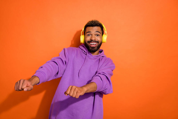 Photo of carefree cheerful man listen new playlist dancing have fun isolated on orange color background. - Photo, Image
