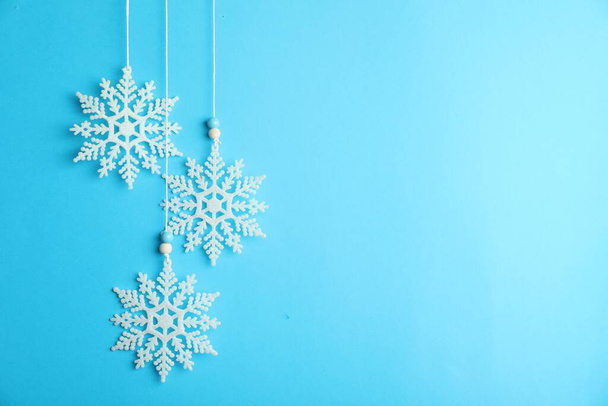 ライトブルーの背景に吊るされた美しい装飾的な雪片、テキストのためのスペース - 写真・画像