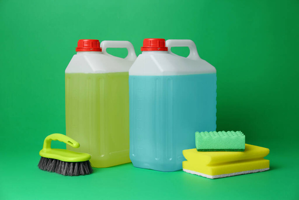 Canisters of detergents and tools on green background. Cleaning supplies - Φωτογραφία, εικόνα