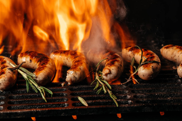 Ψητά λουκάνικα bratwursts μαγείρεμα στην φλεγόμενη σχάρα μπάρμπεκιου ψησίματος πάνω από φλεγόμενα ζεστά κάρβουνα. κρέας στα κάρβουνα. Μορφή μεγάλου banner. - Φωτογραφία, εικόνα