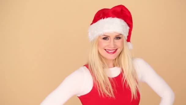 Χαριτωμένο ξανθιά κοπέλα σε ένα γιορτινό κόκκινο καπέλο Santa - Πλάνα, βίντεο