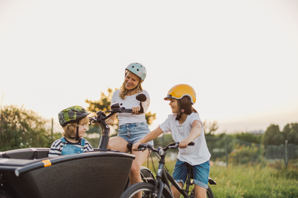 Мать с детьми катается на велосипеде в сельской местности - Фото, изображение