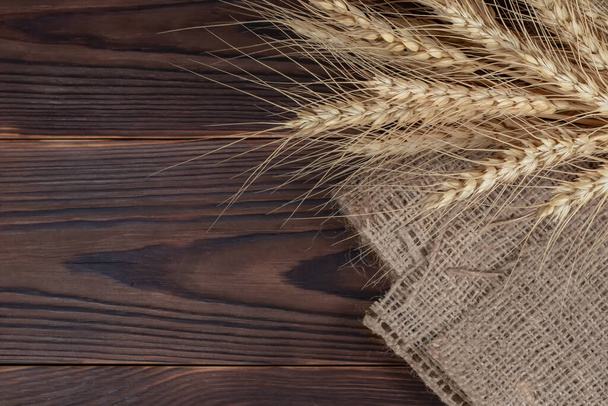 Пшеничные уши на деревянном столе. Пшеничный сноп на фоне леса. Концепция сбора урожая. - Фото, изображение