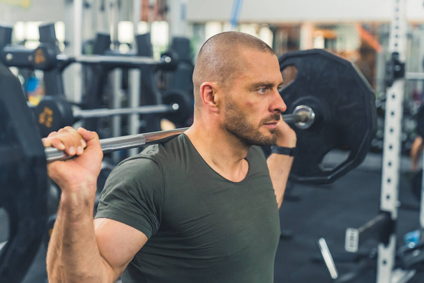 medium closeup portrait of a muscular man workouting with a barbell at the gym, sporty lifestyle . High quality photo - Photo, image