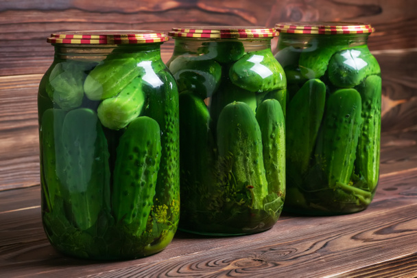 Preservations, conservation. Salted, pickled cucumbers in a jar on an old wooden table. Cucumbers, herbs, dill, garlic. Rustic. Background - Zdjęcie, obraz