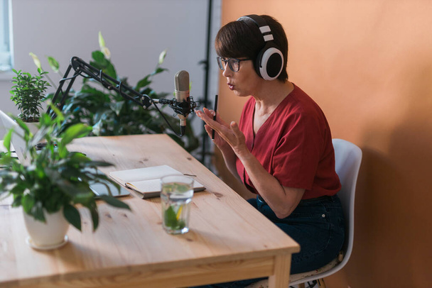 Πορτρέτο της ώριμης γυναίκας φορώντας ακουστικά και μιλώντας σε απευθείας σύνδεση ραδιοφωνικό σταθμό - podcast και εκπομπή - Φωτογραφία, εικόνα
