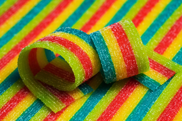 Colorful jelly candies strips in sugar sprinkles. Sour flavored rainbow candy background - Photo, Image