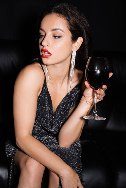femme élégante avec lèvres rouges tenant verre de vin isolé sur noir - Photo, image