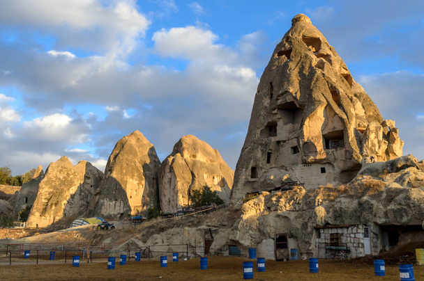 The view on partly collapsed natural rock formations and artificial caves, dovecotes inside it, known as fairy chimneys, located in Goreme, Cappadocia region, Turkey, illuminated by sun - Photo, Image