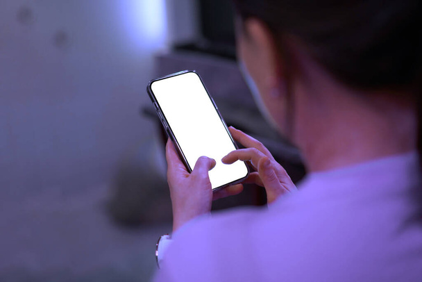 женщина играет мобильный телефон пустой макет экрана снимок сзади - Фото, изображение