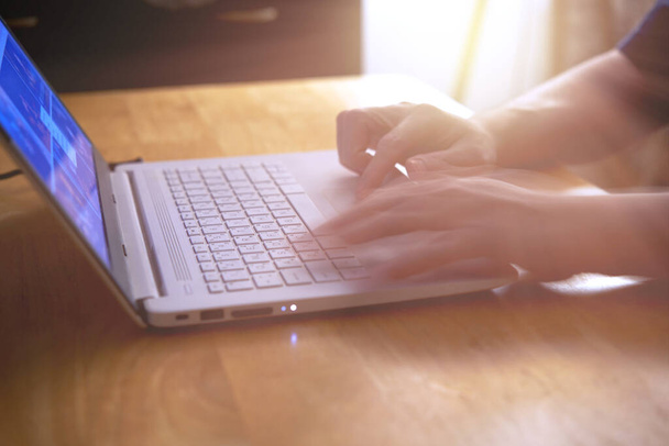 férfi használ laptop számítógép asztalon napfény és mozgás elmosódott kéz - Fotó, kép