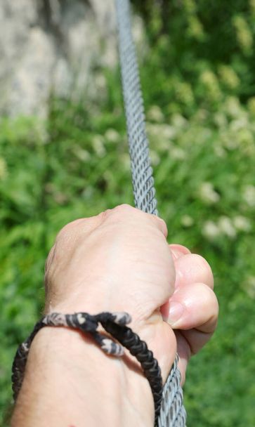 рука человека, крепко держащего верёвку виа феррата в горах во время похода - Фото, изображение
