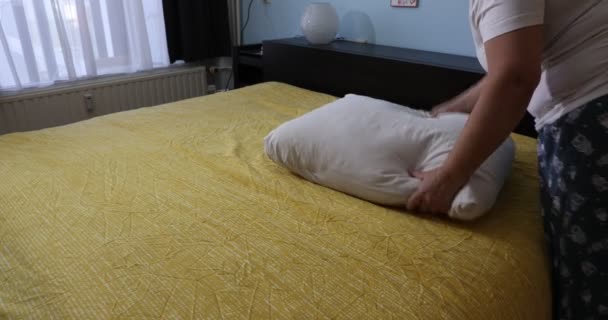 Mulher adulta fazendo a cama e colocando os travesseiros sobre o cobertor amarelo, tarefas domésticas em processo. Conceito de trabalho doméstico em casa - Filmagem, Vídeo