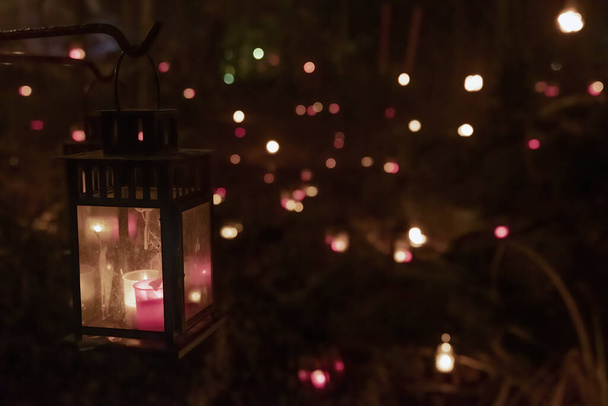 Lantern illuminated in a Dark woods  or forest with several lanterns behind it - Foto, Bild