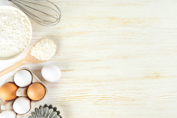 Baking cooking Ingredients background with copy space. Flour, eggs, milk, bakeware on white wooden surface. Top view, flat lay. Mockup menu, banner, header for site, baking concept - Photo, image