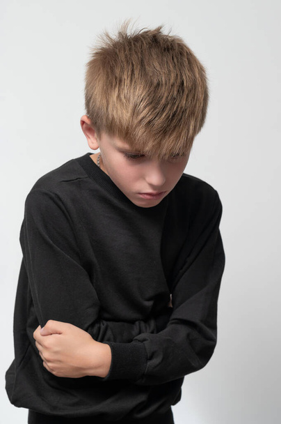The child holds his hands to his stomach from pain, boy on a white background. - Foto, imagen