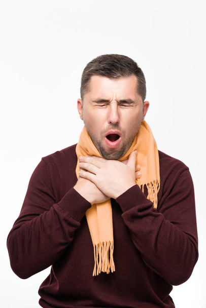 A man suffers from a sore throat, a man wrapped his throat with a scarf, portrait on a white background, severe sore throat. - Fotoğraf, Görsel