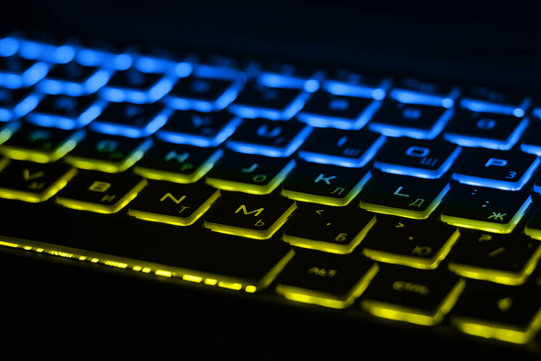Mavi ve sarı arka ışıklandırmalı güzel renkli modern klavye. Ukrayna bayrağının renkleriyle klavyenin arka ışığı - Fotoğraf, Görsel
