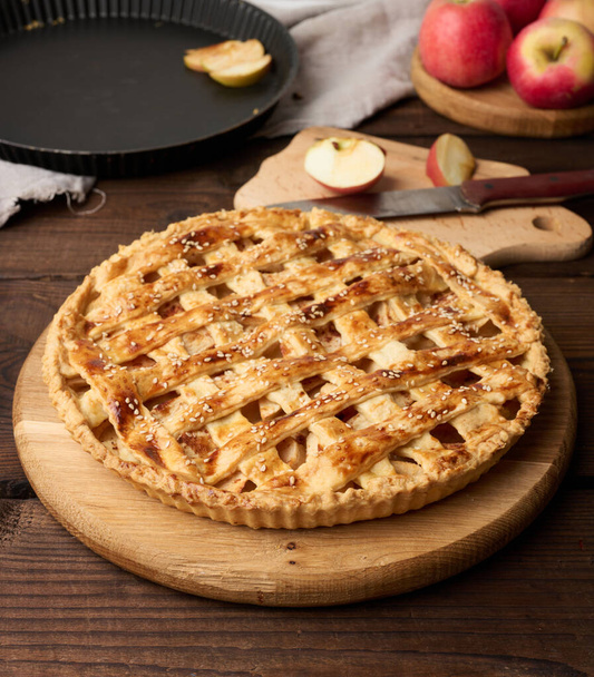 Round baked apple pie on a brown wooden table, top view - Photo, image