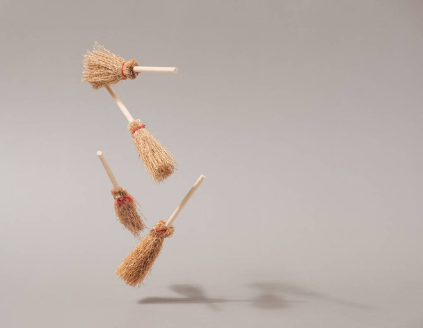 Halloween witch brooms floating against beige background. Witchcraft conceptual backdrop - Fotoğraf, Görsel