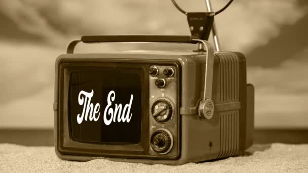 Een vintage televisie op het strand met ouderwetse bioscooptitels die het einde in sepia zeggen - Video