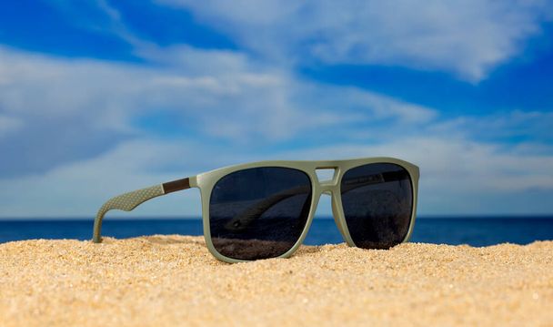 Eine Sonnenbrille am Strand mit Wolken  - Foto, Bild