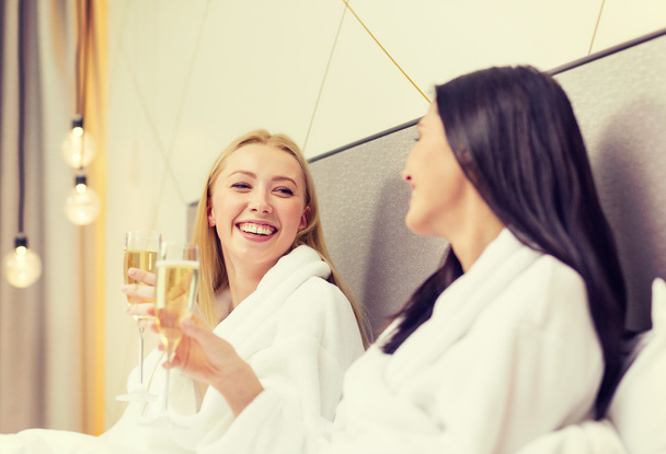 smiling girlfriends with champagne glasses in bed - 写真・画像
