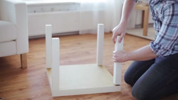 primer plano de las manos masculinas ensamblando las piernas a la mesa
 - Metraje, vídeo