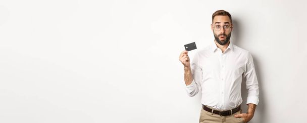 Man looking intrigued and showing credit card. Concept of shopping. - Φωτογραφία, εικόνα