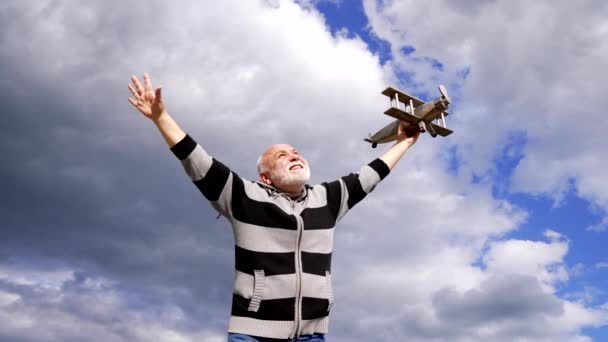 Happy old man pretend flying on model aircraft in sky, pretending. - Footage, Video