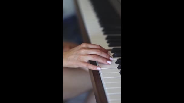 The hand of a young caucasian woman with a delicate white manicure fingering the keys playing the piano,top view close-up with smooth slow motion and depth of field.Music concept,music lesson,music hobby,music education. - Filmati, video