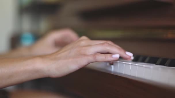 Die Hand einer jungen kaukasischen Frau mit zarter weißer Maniküre, die die Tasten des Klaviers bedient, Nahaufnahme von unten mit sanfter Zeitlupe und Tiefenschärfe.Musikkonzept, Musikunterricht, Musikhobby, Musikerziehung. - Filmmaterial, Video
