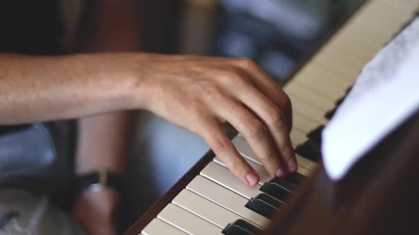 De hand van een jonge Kaukasische man vingeren de toetsen spelen van de piano door noten, zijaanzicht close-up met soepele slow motion en diepte van het veld.Muziekconcept, muziekles, muziekhobby, muziekonderwijs. - Video