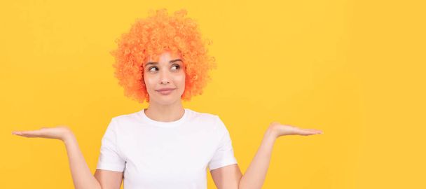 Woman isolated face portrait, banner with copy space. freaky woman in clown wig presenting product. express positive emotions. funny girl in orange wig - 写真・画像