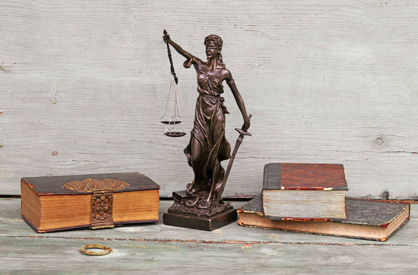 Figura de justicia y libros antiguos sobre fondo de madera. Justicia, escalas y tribunales - Foto, imagen