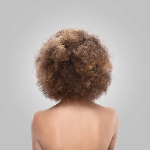 Вид сзади на молодую женщину. Обнаженная брюнетка-кавказка. Кудрявые волосы. Изолированный на сером фоне - Фото, изображение