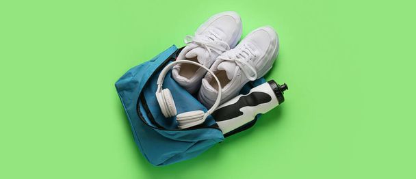 Bolsa con ropa deportiva y equipo sobre fondo verde  - Foto, Imagen